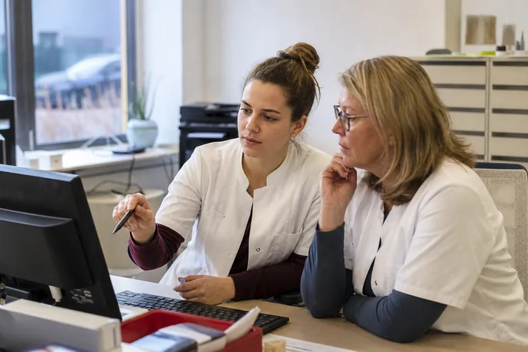 Zwei Apothekenmitarbeitende besprechen eine digitale Rezeptabrechnung