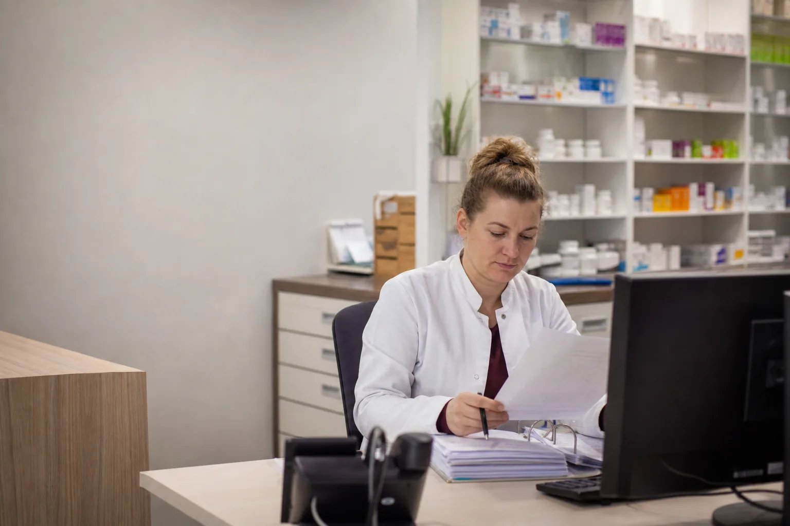 Apothekerin prüft nach Ladenschluss Unterlagen zu einer Retaxation
